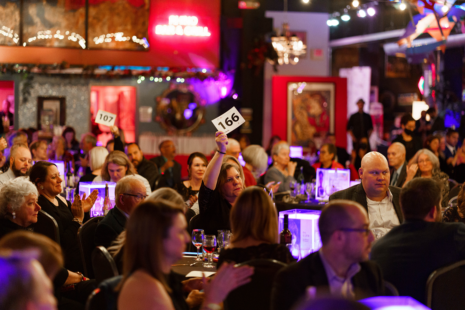 Woman raising paddle at a charity auction